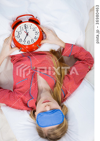 Sleeping woman wearing pajamas holding clock Sleeping woman wearing pajamas holding clock 36980463