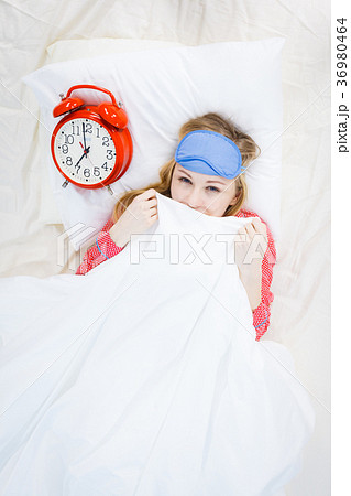 Sleepy woman wearing pajamas holding clock Sleepy woman wearing pajamas holding clock 36980464