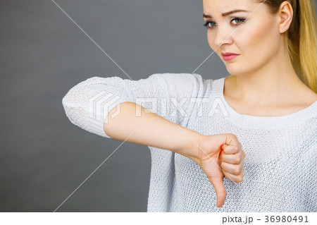 Sad woman showing thumb down gesture Sad woman showing thumb down gesture 36980491