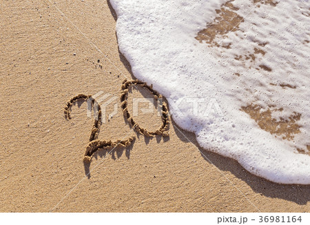 Handwritten inscription 20 on the sand with wave 36981164