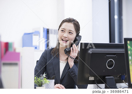 会社の電話で笑顔で話す若い女性社員 会社の電話で笑顔で話す若い女性社員 36986471