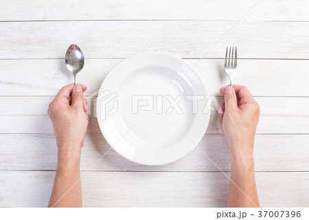 human hand holding a fork and spoon 37007396