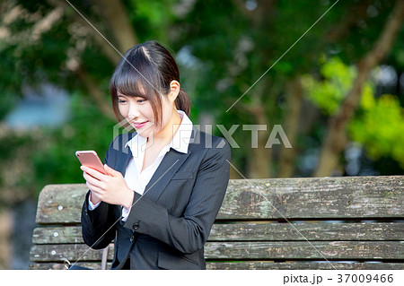 スマホを持ったスーツの女性　OL　ビジネス　スーツ　ポートレート　リクルート　緑背景　 37009466