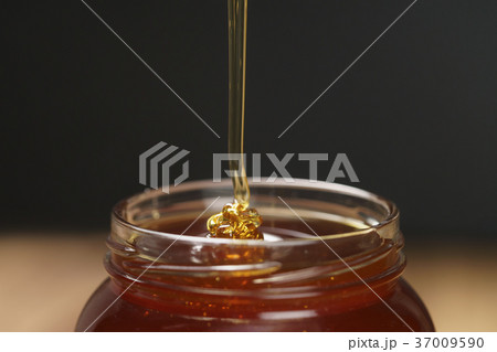 pour honey into glass jar closeup pour honey into glass jar closeup 37009590