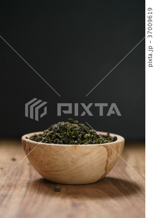 dry organic green oolong tea in wood bowl 37009619