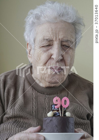 Senior woman blowing candle of her birthday cake Senior woman blowing candle of her birthday cake 37013640
