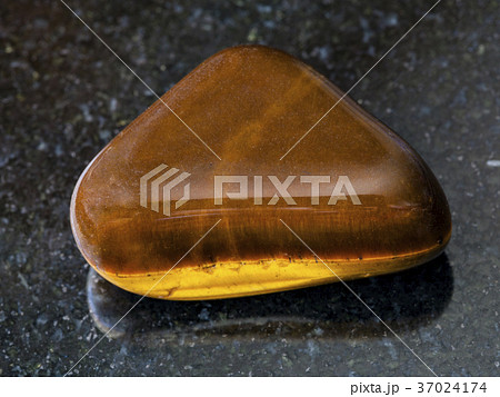 tumbled tiger-eye gem stone on dark background 37024174