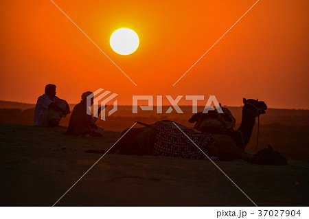 インドのジャイサルメール クーリー村の砂漠 夕日とラクダとラクダ使いの写真素材