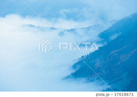 the peaks and clouds above them in blue tones 37028673