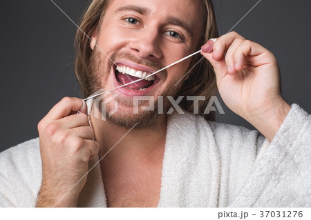 Cheerful young male flossing his teeth Cheerful young male flossing his teeth 37031276