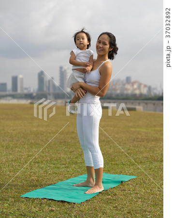 Asian chinese woman practising yoga outdoors with young baby gir 37032892