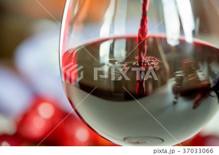 Pouring red wine into the glass against grape 37033066