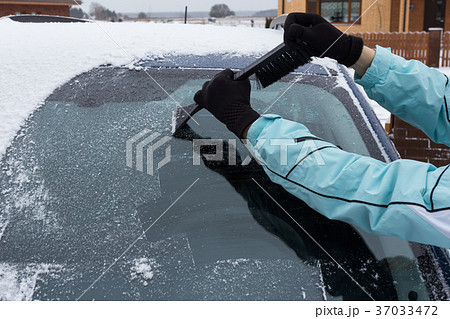 Woman cleaning snow from the car 37033472