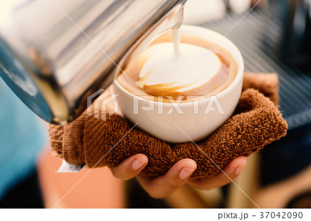 Barista pouring milk into a cup of coffee  37042090