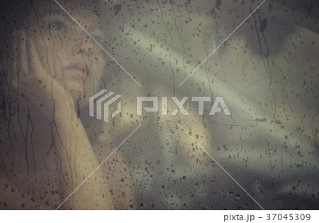 woman looking through the window with rain drop 37045309