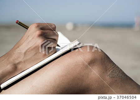 young man writing on the beach young man writing on the beach 37046504