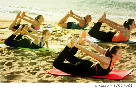 Yoga on beach, group of females practicing 37057031