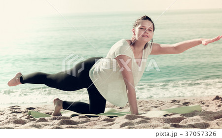 Smiling adult female in white T-shirt is stretching 37057326