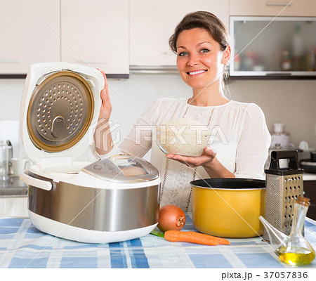 Woman cooking with multicooker at home. 37057836