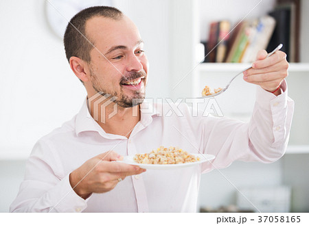 Positive young man eating porridge 37058165