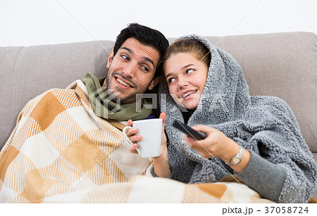 Loving couple snuggling on sofa watching TV Loving couple snuggling on sofa watching TV 37058724