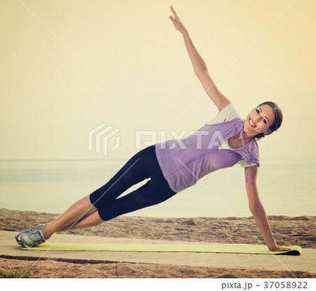 Woman doing exercises on beach by ocean 37058922
