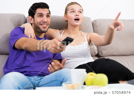Cheerful couple on couch watching TV Cheerful couple on couch watching TV 37058974