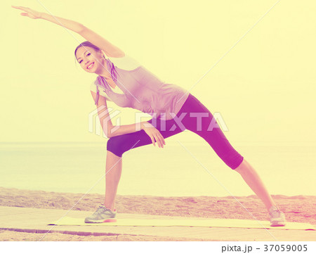 Woman exercising yoga poses on beach 37059005