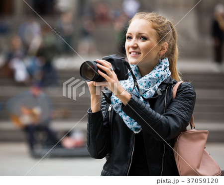 woman walking in autumn city with digital camera 37059120