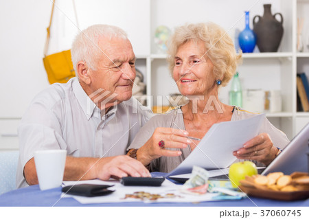 Smiling senior couple counting home finances Smiling senior couple counting home finances 37060745