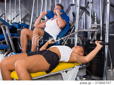 woman making bench press exercise from supine position using gym machinery indoors 37060747