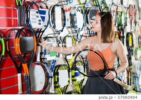 Girl standing in t-shirt in sporting goods store with racket 37060904
