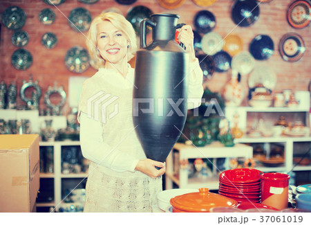 Smiling mature female holding ceramic crockery 37061019