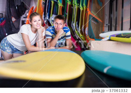 Portrait of smiling surfers choosing new surfboard 37061332