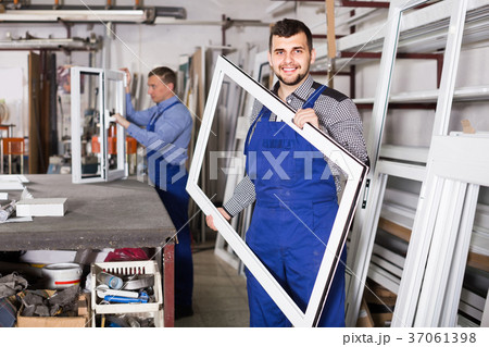 Production workers in coverall with different finished PVC profiles and windows at factory Production workers in coverall with different finished PVC profiles and windows at factory 37061398