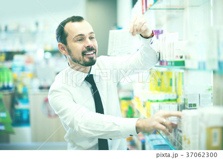 Smiling man customer looking rows of pills Smiling man customer looking rows of pills 37062300