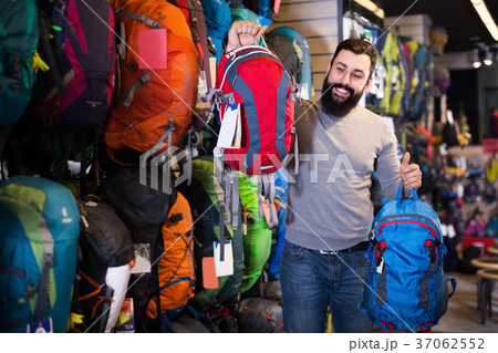 Young male customer examining backpacks in store 37062552