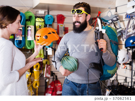 Climbers examining alpinism equipment items in sports shop Climbers examining alpinism equipment items in sports shop 37062561