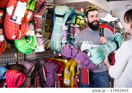 Positive man choosing alpinism cables in sports store Positive man choosing alpinism cables in sports store 37062605