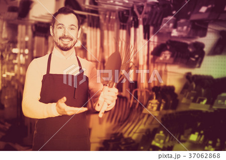 Seller displaying various items in garden equipment shop 37062868