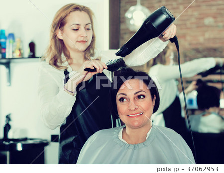 Hairdresser styling and drying hair with fen and brush of women 37062953