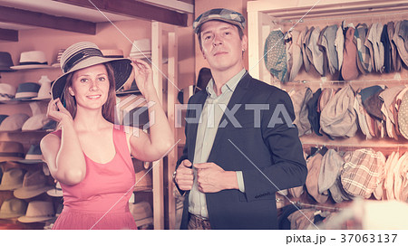 Positive woman and man trying on fashion hats 37063137