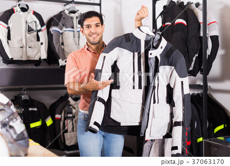 Man is demonstrating new jacket for motorbike in the store. 37063170
