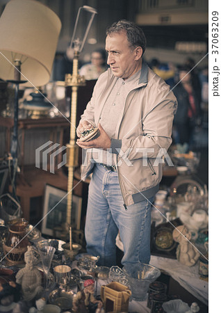 Man is visiting market of old things, choosing old casket 37063209