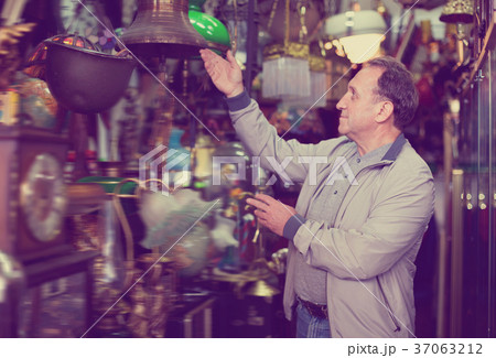 Positive elderly man choosing interesting souvenirs at traditional flea market 37063212