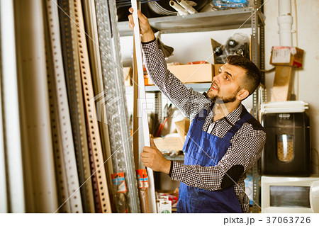 Young man worker examining plastic corners for tiles and floors Young man worker examining plastic corners for tiles and floors 37063726