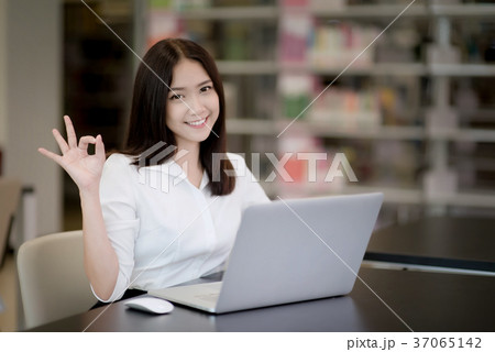 Happy Asian young woman using laptop in office Happy Asian young woman using laptop in office 37065142