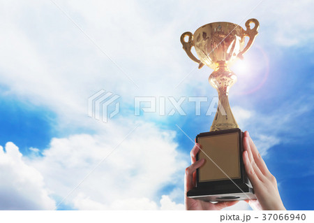 Hands holding trophy cup on sky background. 37066940