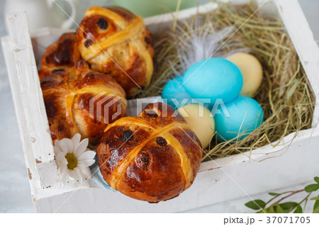 Easter cross buns in a wooden box, painted eggs. Easter cross buns in a wooden box, painted eggs. 37071705