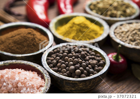 A selection of various colorful spices on a wooden table in bowl 37072321